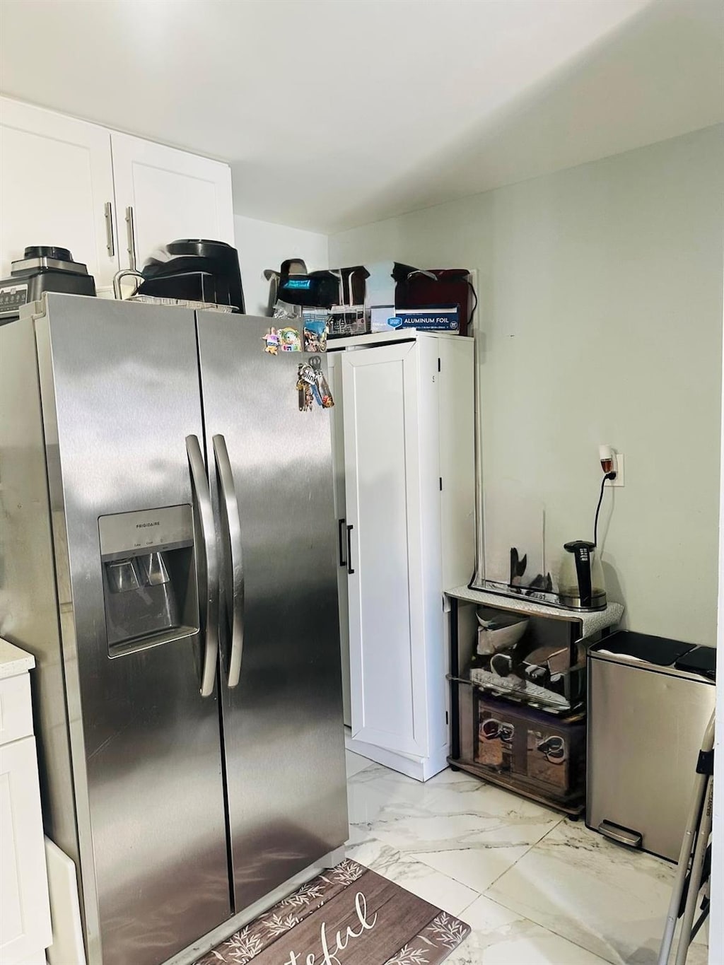 kitchen featuring marble finish floor, white cabinetry, and stainless steel fridge with ice dispenser