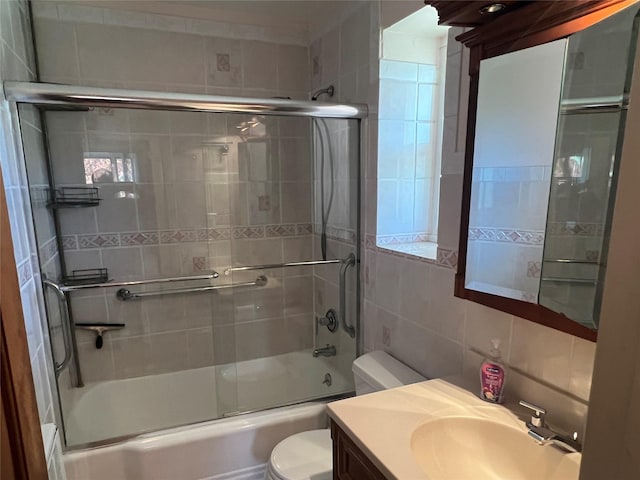 full bathroom with vanity, decorative backsplash, toilet, tile walls, and combined bath / shower with glass door