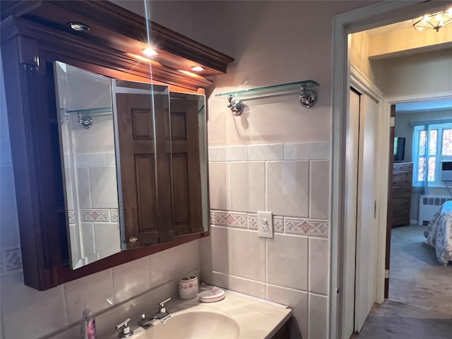 bathroom featuring radiator heating unit, tile walls, and a sink