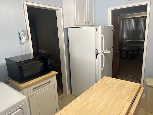 kitchen with black microwave, white cabinets, freestanding refrigerator, radiator heating unit, and butcher block countertops