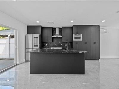 66-39 Jay Ave, Maspeth, NY 11378 - kitchen featuring decorative backsplash, dark countertops, an island with sink, smart refrigerator, and wall chimney range hood