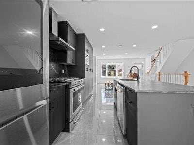 66-39 Jay Ave, Maspeth, NY 11378 - kitchen featuring appliances with stainless steel finishes, a sink, dark cabinetry, a large island with sink, and modern cabinets