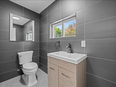 66-39 Jay Ave, Maspeth, NY 11378 - bathroom featuring vanity, toilet, and tile walls