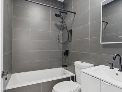66-39 Jay Ave, Maspeth, NY 11378 - full bathroom featuring tiled shower / bath combo, tile walls, vanity, and toilet