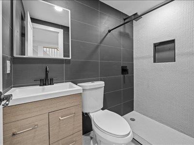 66-39 Jay Ave, Maspeth, NY 11378 - full bath featuring vanity, a tile shower, toilet, and tile walls