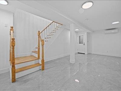 66-39 Jay Ave, Maspeth, NY 11378 - finished below grade area featuring stairway, baseboards, and an AC wall unit