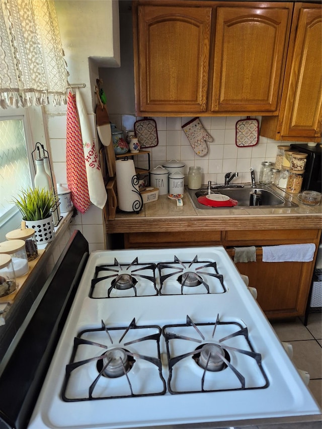 3238 Tenbroeck Ave, Bronx, NY 10469 - kitchen featuring range with gas cooktop, tasteful backsplash, brown cabinets, a sink, and light countertops