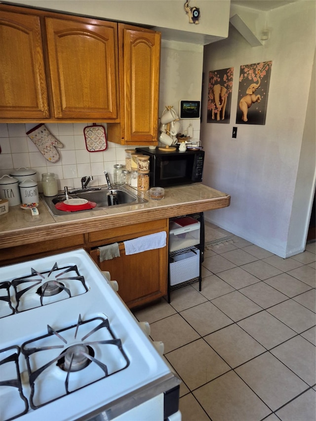 3238 Tenbroeck Ave, Bronx, NY 10469 - kitchen with light tile patterned flooring, black microwave, a sink, brown cabinetry, and range with gas cooktop