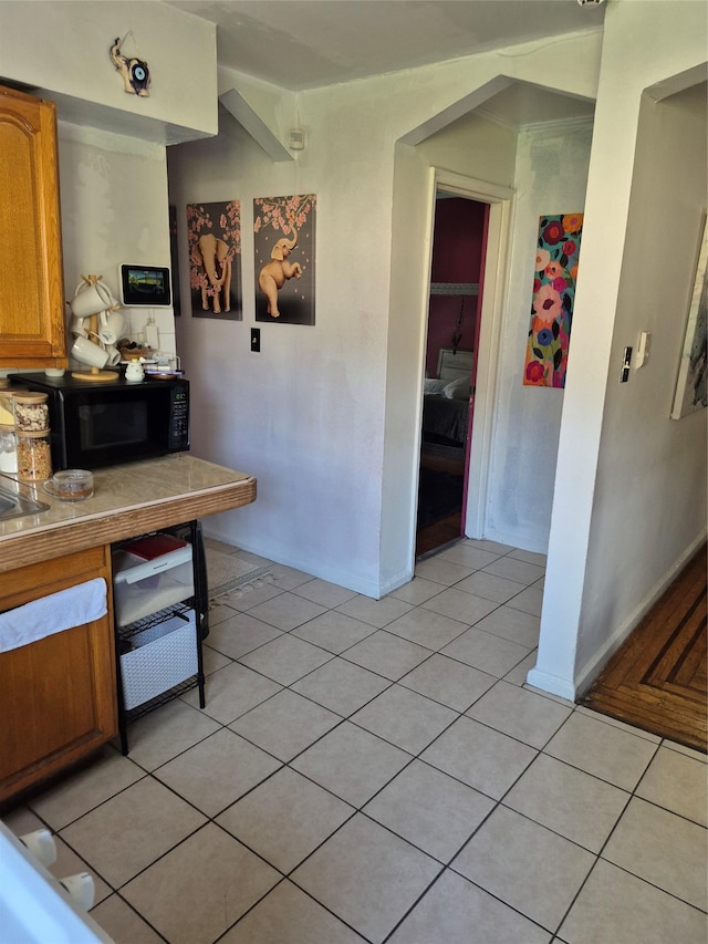 3238 Tenbroeck Ave, Bronx, NY 10469 - kitchen with black microwave, brown cabinets, light tile patterned floors, baseboards, and light countertops