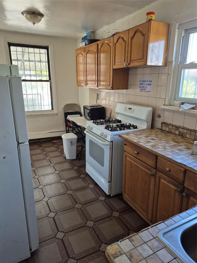 3238 Tenbroeck Ave, Bronx, NY 10469 - kitchen featuring brown cabinetry, white appliances, tile countertops, tasteful backsplash, and a baseboard radiator
