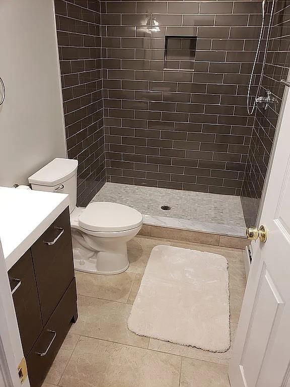 full bath featuring vanity, tile patterned flooring, a shower stall, and toilet
