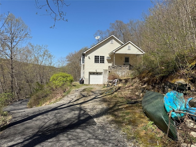 view of front facade featuring an attached garage, driveway, and a wooded view