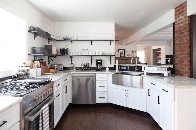 kitchen featuring open shelves, a sink, appliances with stainless steel finishes, and a peninsula