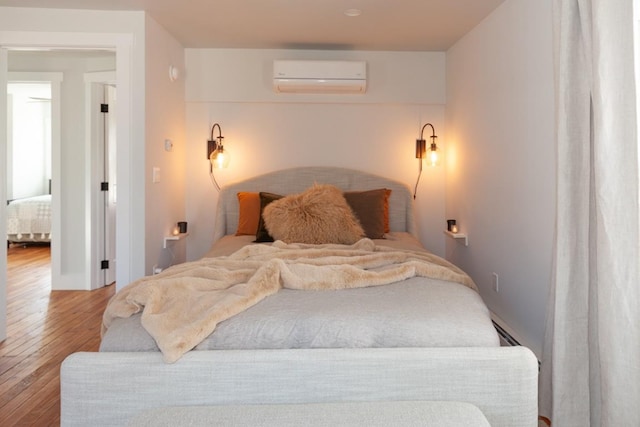 bedroom featuring a wall unit AC and wood finished floors