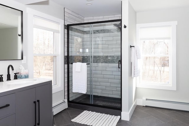 full bathroom featuring vanity, tile patterned flooring, baseboard heating, and a stall shower