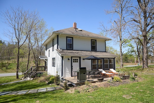 rear view of property with roof with shingles, a chimney, a yard, and a deck