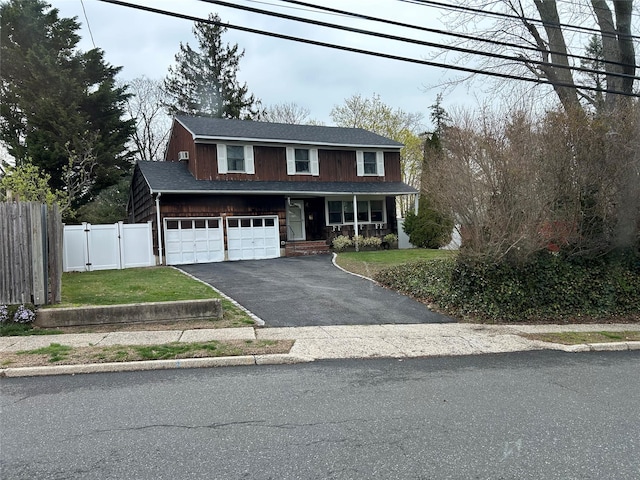 traditional home featuring fence, a front lawn, a garage, covered porch, and driveway