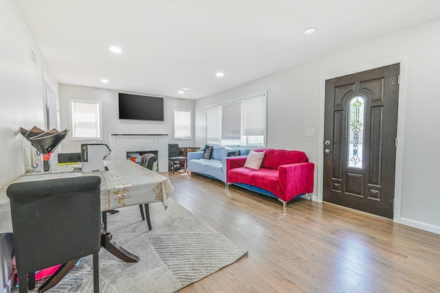 living area with a brick fireplace, recessed lighting, baseboards, and wood finished floors