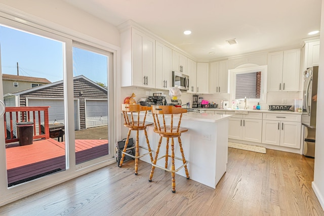 kitchen featuring visible vents, appliances with stainless steel finishes, tasteful backsplash, white cabinets, and light wood finished floors