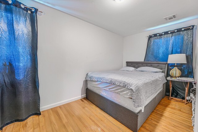 bedroom featuring baseboards, wood finished floors, and visible vents