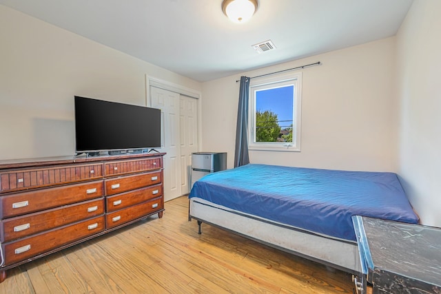 bedroom with visible vents, light wood-style flooring, and a closet