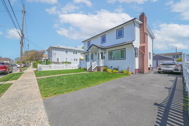 view of front of house featuring fence, a chimney, and a front yard