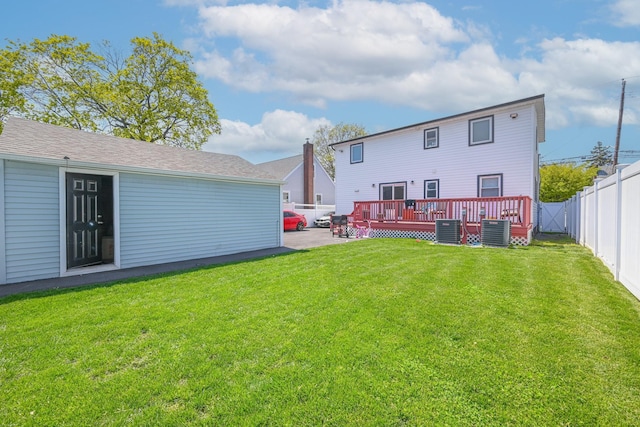 rear view of property with central air condition unit, a lawn, a fenced backyard, and a deck