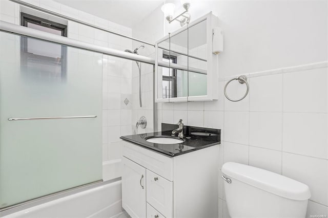 bathroom with shower / bath combination with glass door, vanity, toilet, tile walls, and decorative backsplash