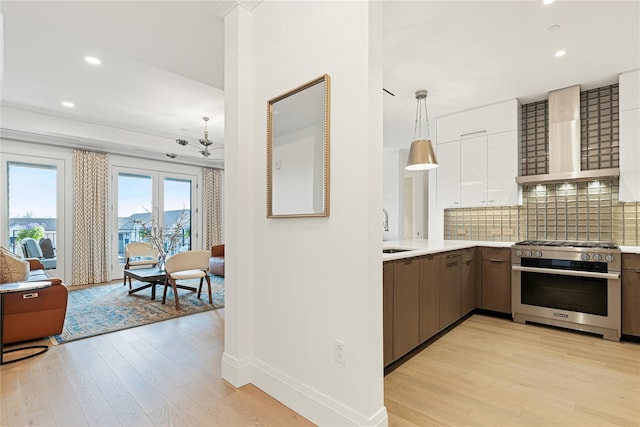kitchen featuring light countertops, wall chimney exhaust hood, light wood finished floors, and high end stainless steel range