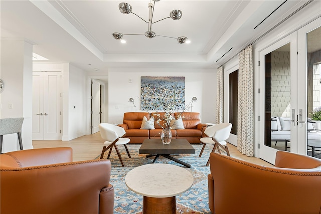 living room with french doors, baseboards, a chandelier, light wood-style floors, and a tray ceiling
