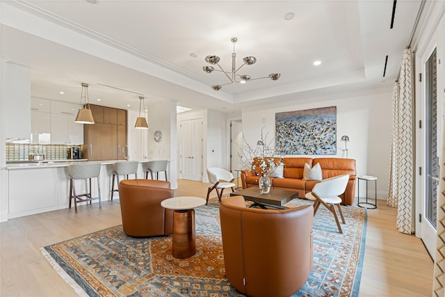 living area with light wood-type flooring, recessed lighting, a notable chandelier, and a tray ceiling