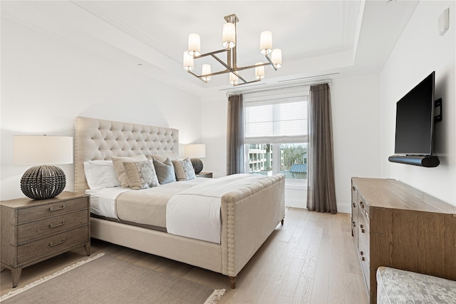 bedroom with a notable chandelier, baseboards, light wood-type flooring, a tray ceiling, and ornamental molding