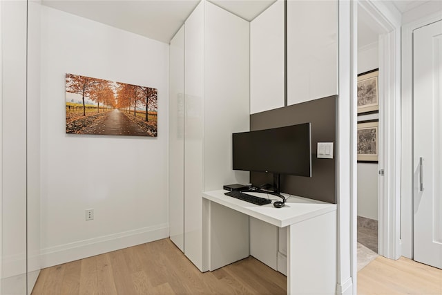 unfurnished office with baseboards and light wood-style flooring