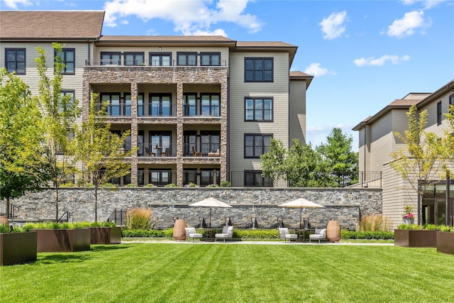 back of property featuring a lawn and stone siding