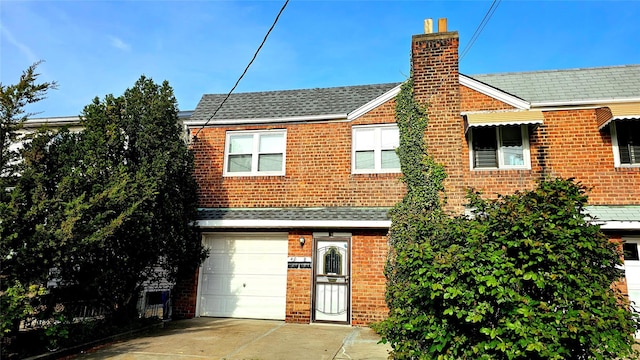 view of front of house with a chimney, an attached garage, driveway, and brick siding