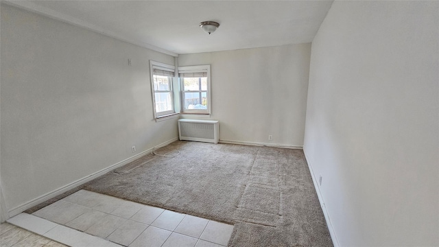 empty room featuring radiator, baseboards, and carpet