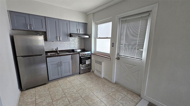 kitchen with gray cabinets, a sink, under cabinet range hood, radiator, and stainless steel appliances