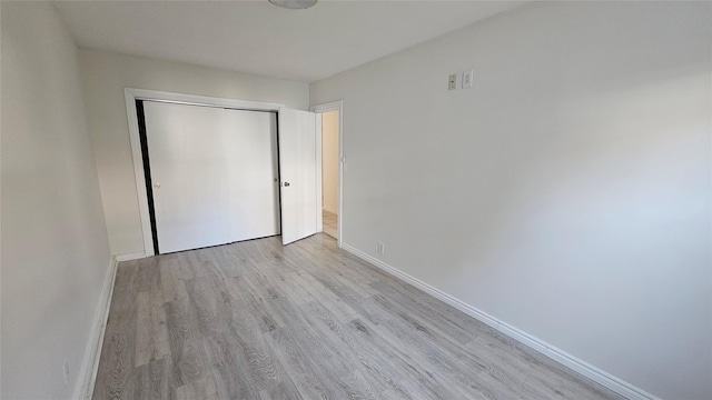unfurnished bedroom featuring baseboards, wood finished floors, and a closet