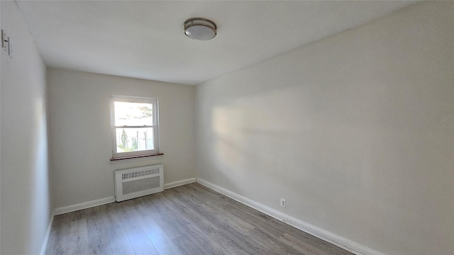 spare room with baseboards and wood finished floors