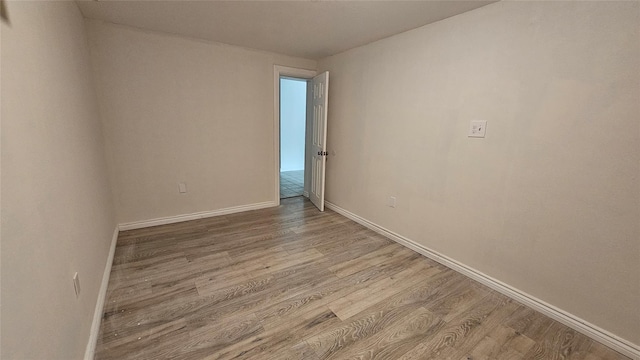 spare room with baseboards and wood finished floors