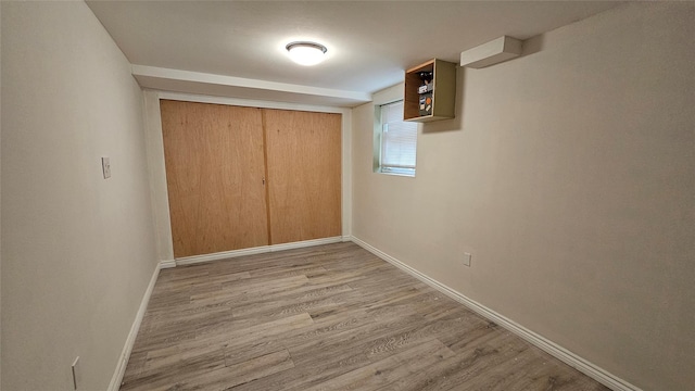 unfurnished bedroom featuring light wood-type flooring, baseboards, and a closet