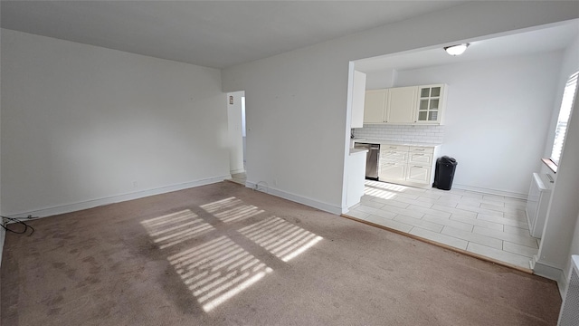 unfurnished living room featuring baseboards and light carpet