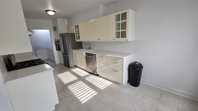 kitchen featuring tasteful backsplash, a sink, light countertops, light tile patterned floors, and stainless steel appliances