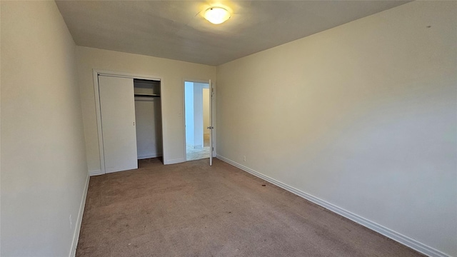 unfurnished bedroom featuring baseboards, light carpet, and a closet