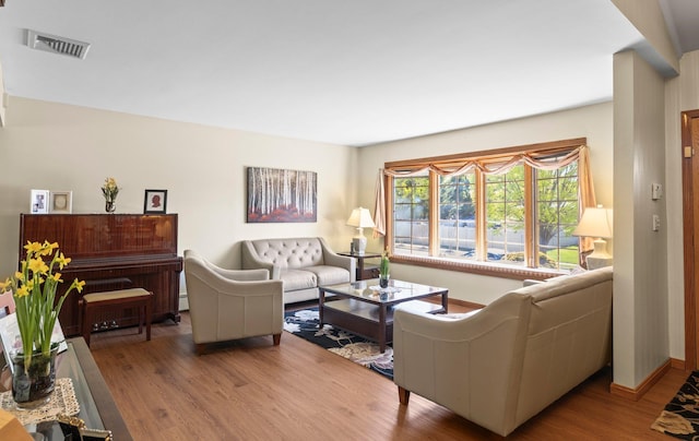 living room featuring visible vents, baseboards, and wood finished floors