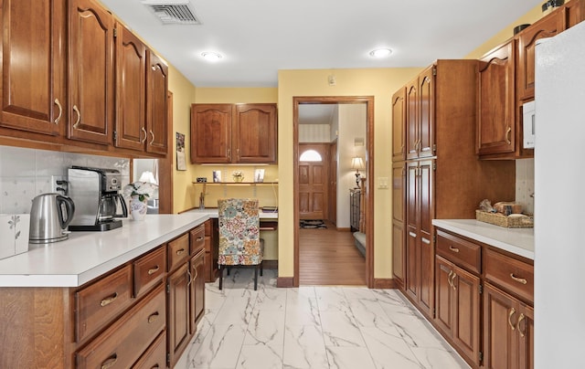 kitchen with visible vents, tasteful backsplash, brown cabinets, light countertops, and marble finish floor
