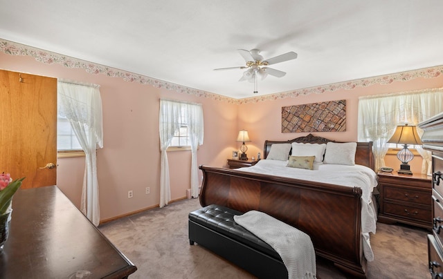 bedroom with baseboards, a ceiling fan, multiple windows, and light carpet