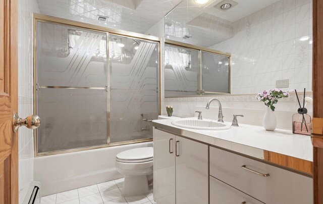 bathroom with vanity, toilet, tile walls, combined bath / shower with glass door, and a baseboard radiator
