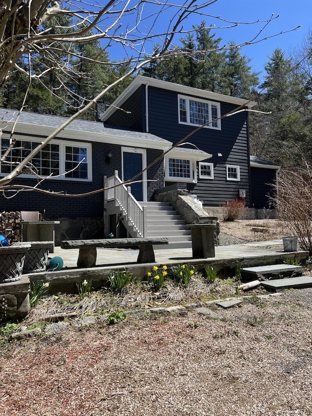 view of front facade featuring stairs and brick siding