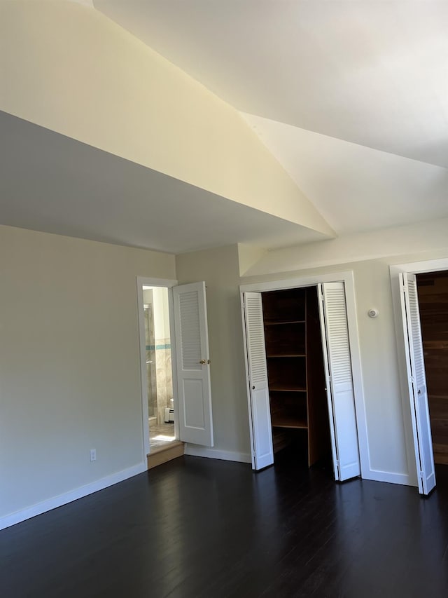 unfurnished bedroom with baseboards, dark wood-style flooring, baseboard heating, and a closet
